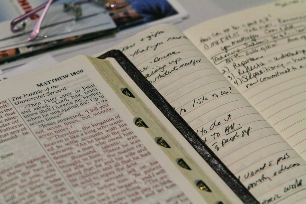 A photo of an open Bible next to a notebook